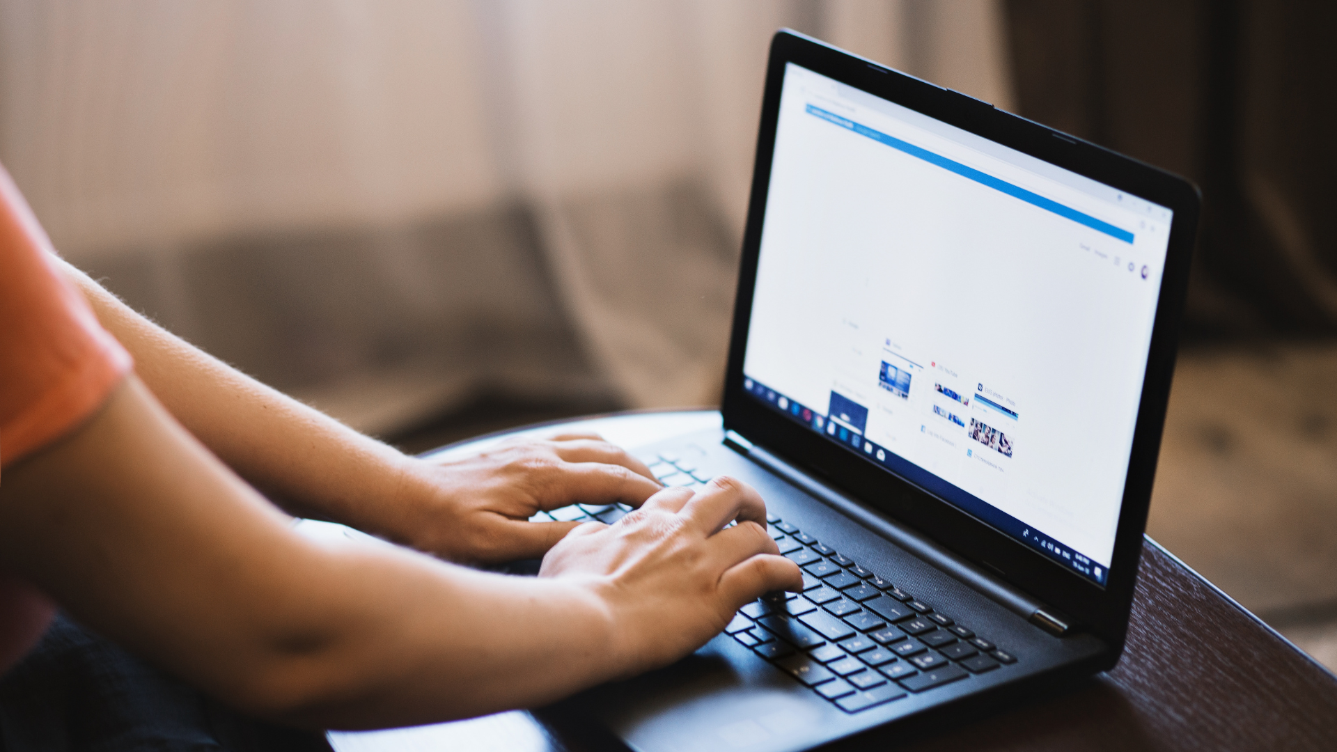 Laptop, widoczne ręce dotykające klawiatury komputera